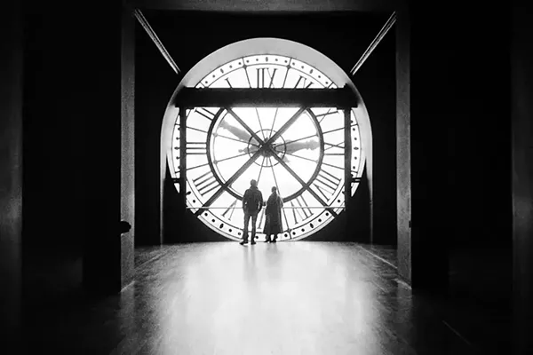 black and white picture of a couple silhouette in front of orsay museum clock in paris